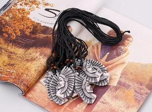 Détail d'un collier pendentif chef indien vintage avec plumes blanches et perles en bois