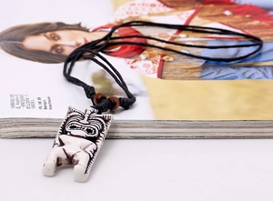 Gros plan d'un pendentif totem ethnique en résine sur cordon ciré noir et perles en bois