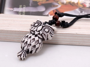 Detail of hand-carved owl pendant with ethnic resin texture and wooden beads