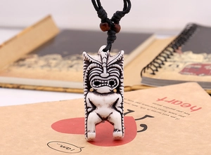 Gros plan d'un pendentif tiki tribal en résine avec cordon noir et perles en bois