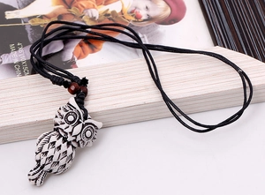 Macro detail of owl pendant necklace with etched feathers and black braided rope