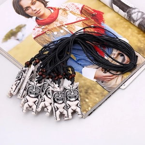 Collier pendentif tiki tribal avec corde cirée noire et perles en bois sur fond ethnique