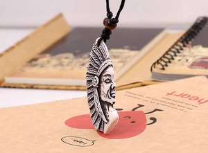 Détail d'un pendentif gravé de chef de tribu ethnique avec cordon noir et perles en bois