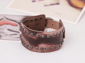 Détail d'un large bracelet en cuir marron rétro orné de deux rangées de rivets en métal