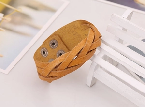 Detail of yellow braided leather wide bracelet showing texture and metal snap buttons