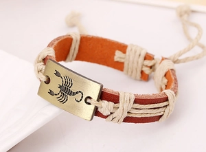 Close-up of vintage leather bracelet featuring a bronze Scorpio charm with woven details
