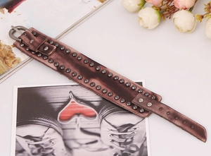 Vue détaillée d'un bracelet en cuir vintage brun-rouge avec rivets en métal et boucle