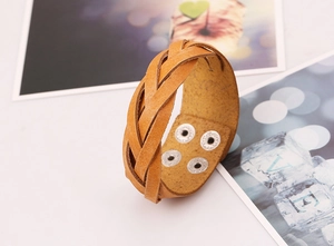 Macro view of ginger yellow braided leather bracelet with four silver metal snap buttons