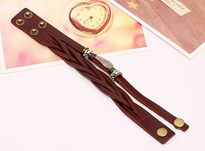 Detail view of woven brown leather punk bracelet featuring vintage silver feather charm