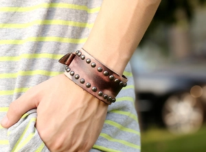 Gros plan d'un bracelet large en cuir marron style punk avec deux rangées de rivets