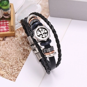 Close-up of multilayer braided leather bracelet with vintage metal cross arrow charm