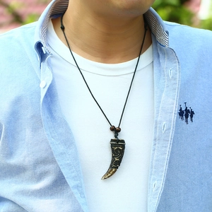 Close-up of a rustic wolf tooth pendant necklace on a male model with natural light