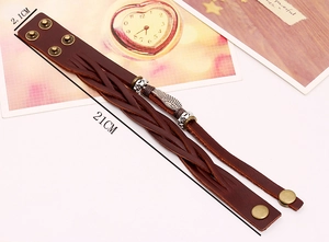 Detail view of vintage brown leather woven bracelet with metal wing and size markings