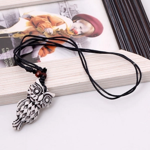 Retro owl pendant necklace with resin carving and black woven cord on white background