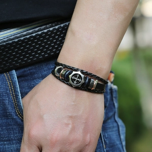 Detail of men's layered leather bracelet with silver shield cross and metallic beads