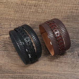 Détail de bracelets en cuir tressé multicouches en noir et marron avec fermoir métallique