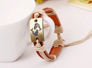 Detail of Pisces constellation bronze plaque on a woven brown leather bracelet