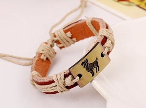 Close-up of woven leather bracelet with bronze Aries zodiac sign on a ceramic plate