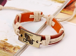 Macro shot of a vintage Capricorn bronze zodiac charm on a red leather braided bracelet