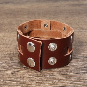 Close-up of vintage wide leather bracelet featuring metal rivets and snap buttons