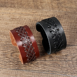 Close-up of brown and black woven leather bracelets on a dark wooden background