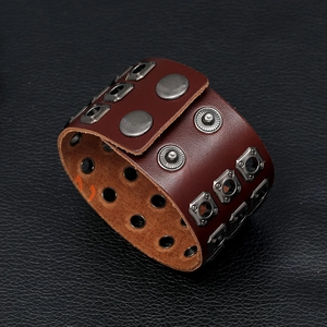 Macro view of dark brown leather punk bracelet featuring silver metal studs and snap buttons