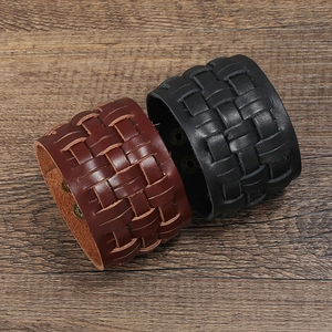 Retro multi-layer braided leather bracelets in black and brown on vintage wood surface