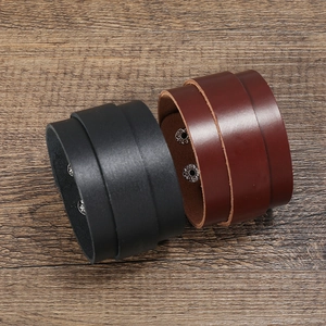 Wide black and brown leather punk bracelets with silver snap buttons on wood background