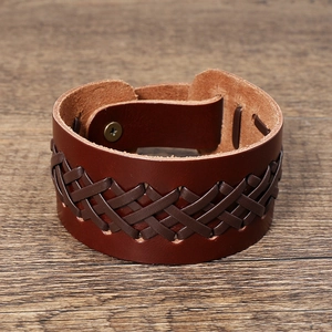 Detail view of woven leather bracelet with cross metallic snap on wooden surface
