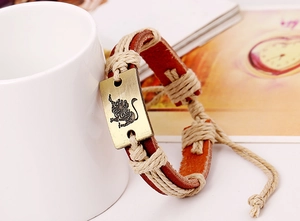 Detail of vintage leather bracelet featuring a bronze Leo zodiac charm on a woven band
