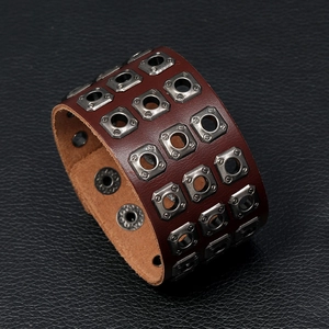 Detail of vintage brown leather punk bracelet featuring triple row square metal eyelets