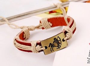 Detailed macro view of Sagittarius bronze metal plate on a brown woven leather bracelet