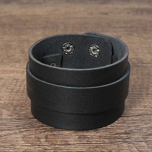 Macro detail of wide black leather punk bracelet showing texture and metal snaps