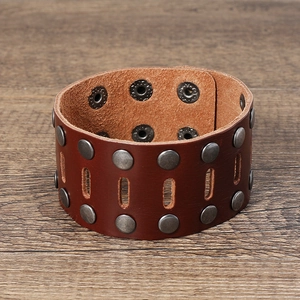 Detail of punk style wide leather bracelet featuring double rows of silver metal rivets