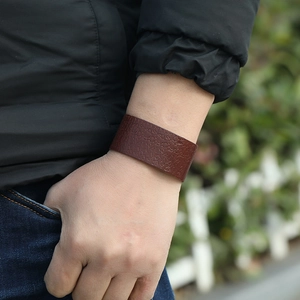Détail macro du large bracelet en cuir marron foncé avec motif de texte vintage embossé