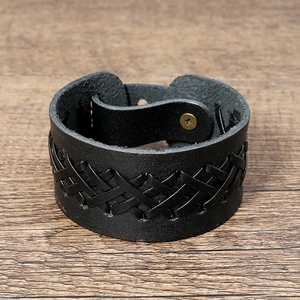 Detailed view of black braided leather cuff bracelet with bronze snap closure