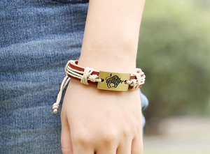 Close-up of a bronze Taurus zodiac metal plate on a brown leather braided bracelet
