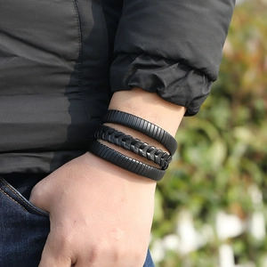 Vue rapprochée d'un ensemble de trois bracelets noirs en cuir tressé porté par un homme