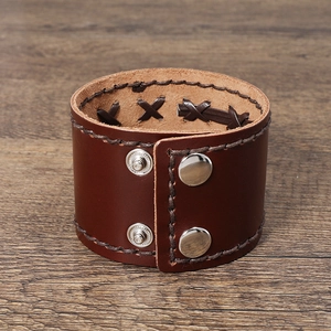 Detailed view of wide brown leather bracelet featuring woven craft and metal snap fasteners