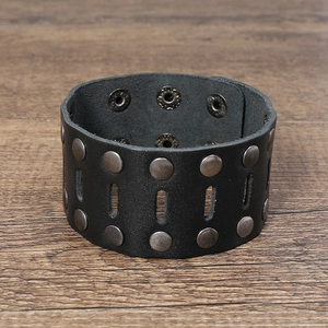 Detail of black leather cuff featuring double-row bronze rivets and punk style cutouts