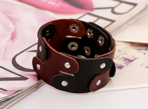 Detailed view of layered brown and black leather punk bracelet with silver metal snap buttons