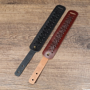 Close-up of black and brown braided leather bracelets on a wooden surface
