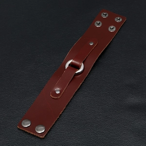 Macro detail of dark brown leather punk bracelet with polished silver metal ring buckle