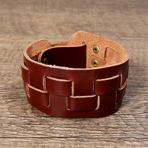 Close-up of brown multilayer braided leather cuff with bronze snap buttons on wood
