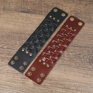 Close-up of woven leather bracelets in black and brown with vintage bronze snaps