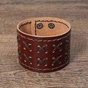 Detail of dark brown leather wide cuff with triple-row cross stitching and metal snaps