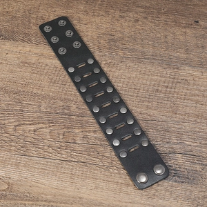 Detail of black leather punk bracelet with double-row metal rivets on wood background