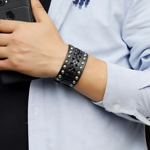 Close-up of men's wide punk leather bracelet featuring metal rivets and braided texture