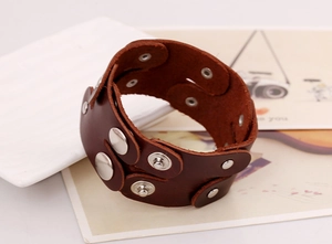 Detail view of dark brown wide leather punk bracelet with double-row metal snap buttons