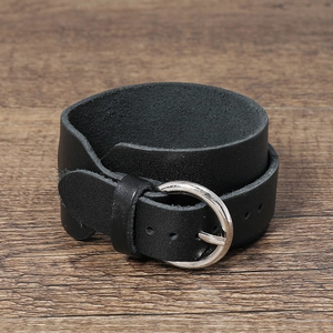 Close-up of black double-wrap leather bracelet with silver metal buckle on wood surface